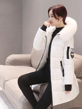 Woman wearing a white winter coat with a fur-lined hood in a neutral setting