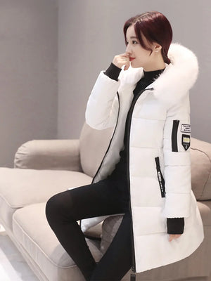 Woman wearing a white winter coat with a fur-lined hood in a neutral setting