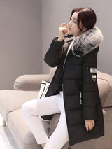 Woman wearing a black winter coat with fur hood sitting on a couch.
