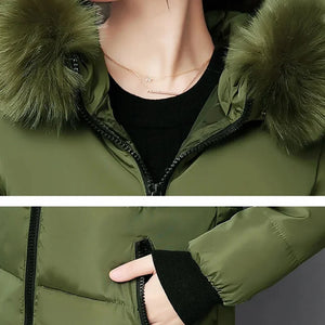 Green winter jacket with fur-lined hood and black cuffs on a neutral background