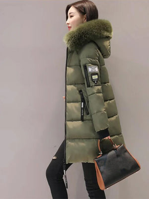 Green winter coat with fur hood worn by a person on a gray background
