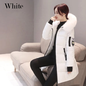 Person wearing a white winter coat sitting on a couch with a neutral background