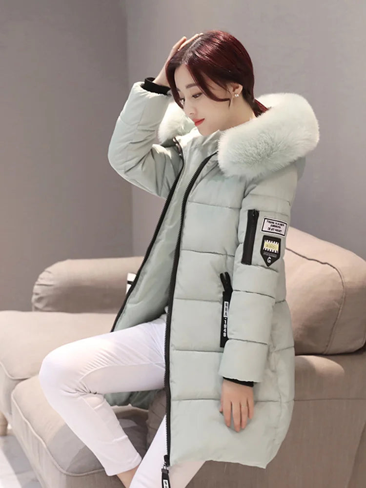 Person wearing a gray winter coat with a fur-lined hood sitting on a couch.