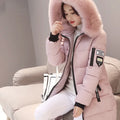 Person wearing a pink winter coat with fur hood sitting on a couch.