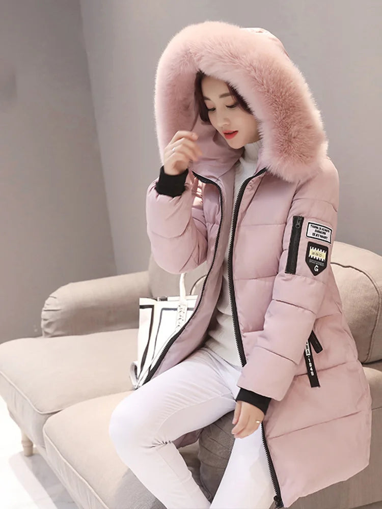 Person wearing a pink winter coat with fur hood sitting on a couch.