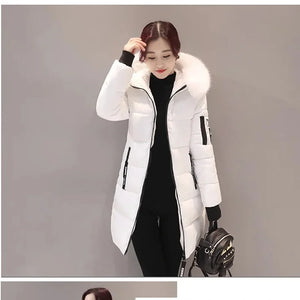 Woman wearing a white winter coat with fur hood on a gray background