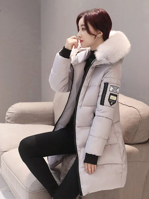 Person wearing a gray winter coat with a fur-lined hood sitting on a beige couch.
