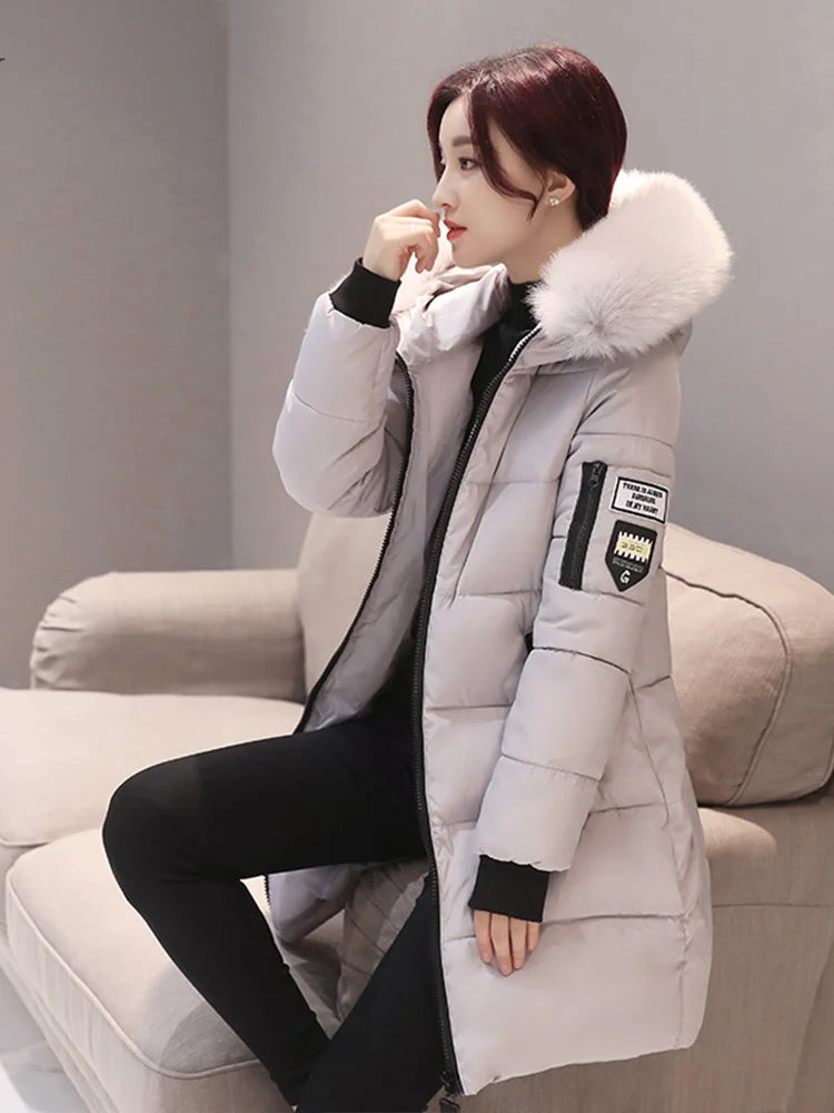Person wearing a gray winter coat with a fur-lined hood sitting on a beige couch.