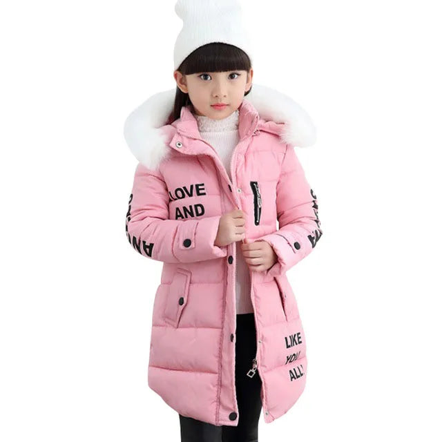 Pink winter coat with fur hood worn by a child on a white background