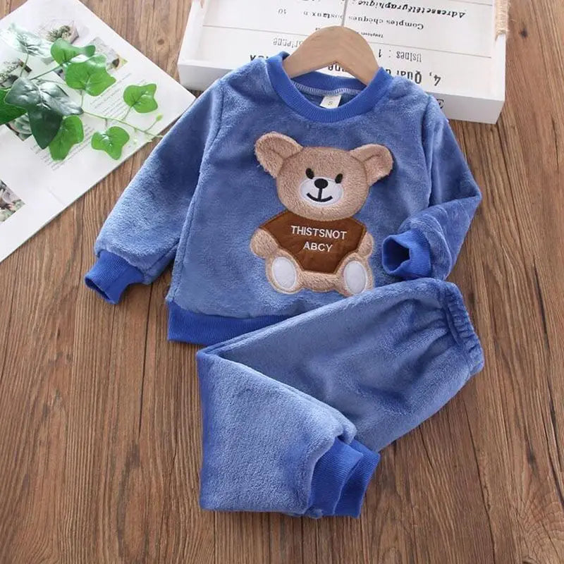 Blue children's fleece set with teddy bear design on a wooden surface