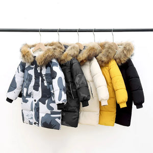 Collection of winter jackets with fur hoods on a rack against a white background