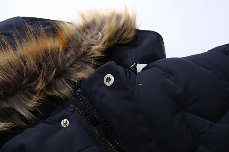 Close-up of a dark blue winter coat with a fur-lined hood on a light gray background