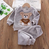 Children's gray outfit with teddy bear design on a wooden surface