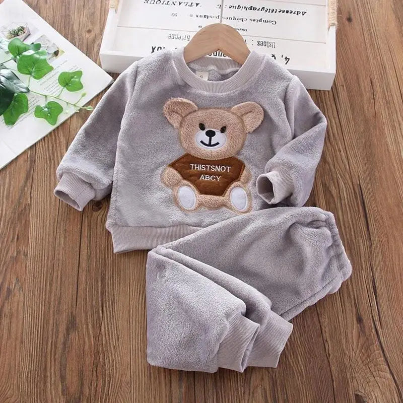 Children's gray outfit with teddy bear design on a wooden surface