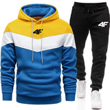 Color-blocked hoodie and black pants with a brand logo on a white background