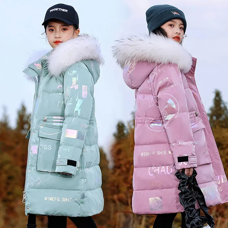 Two people wearing long puffer jackets with fur hoods in a forest setting.