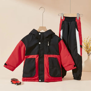 Red and black jacket and pants set on hangers with a small toy car on a beige background