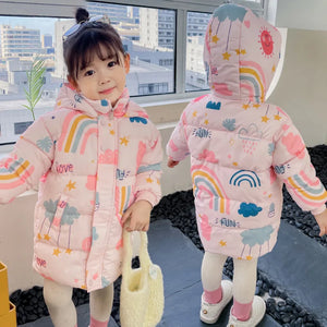 Two children wearing pink hoodies with rainbow and cloud patterns indoors.