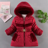Red children's coat with fur trim on a gray surface