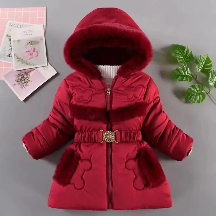 Red children's coat with fur trim on a gray surface