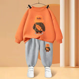 Orange sweatshirt with a cartoon character and gray pants on a hanger against an orange wall.