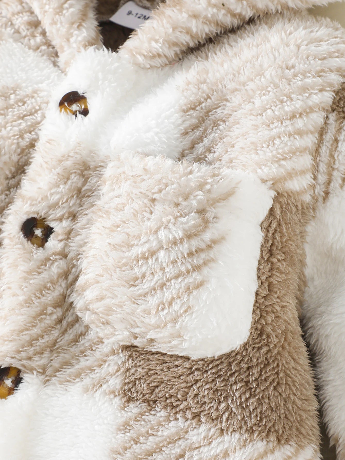 Close-up of a fluffy, beige and white animal-shaped blanket with a bee design.