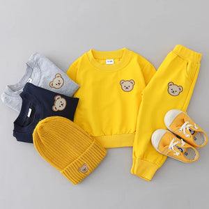 Yellow children's outfit with teddy bear design on a gray background