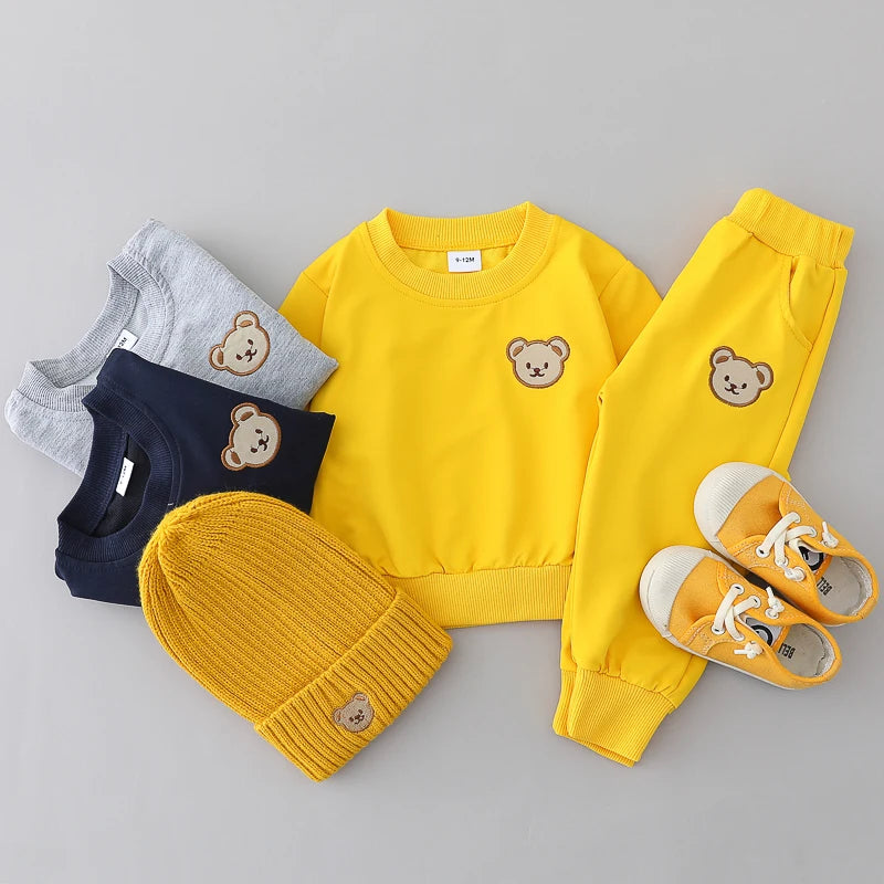 Yellow children's outfit with teddy bear design on a gray background