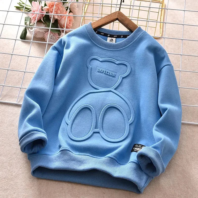 Blue sweater with bear design on a hanger against a grid background