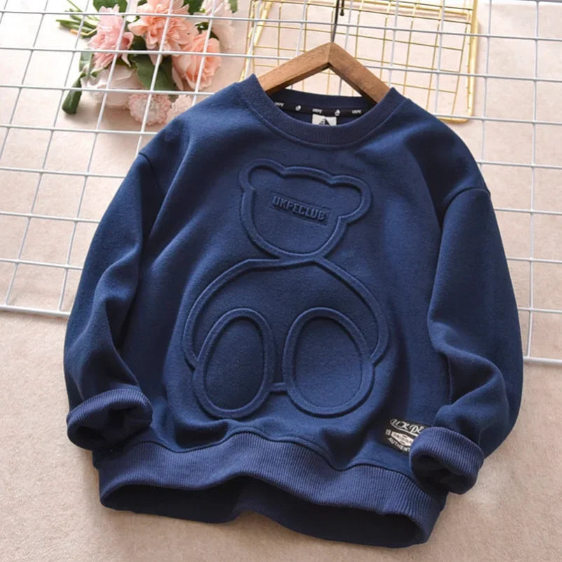 Blue sweater with bear design on a hanger against a grid background