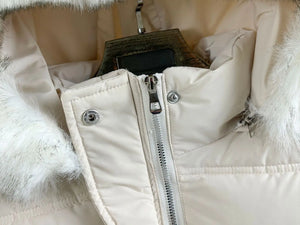 Close-up of a white puffer jacket with fur trim on a hanger.