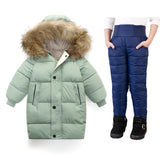 Green winter coat with fur hood and blue snow pants on a white background