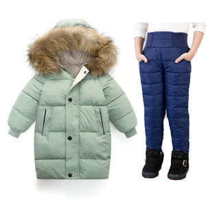 Green winter coat with fur hood and blue snow pants on a white background