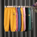 Colorful sweatpants hanging on a rack against a dark curtain background