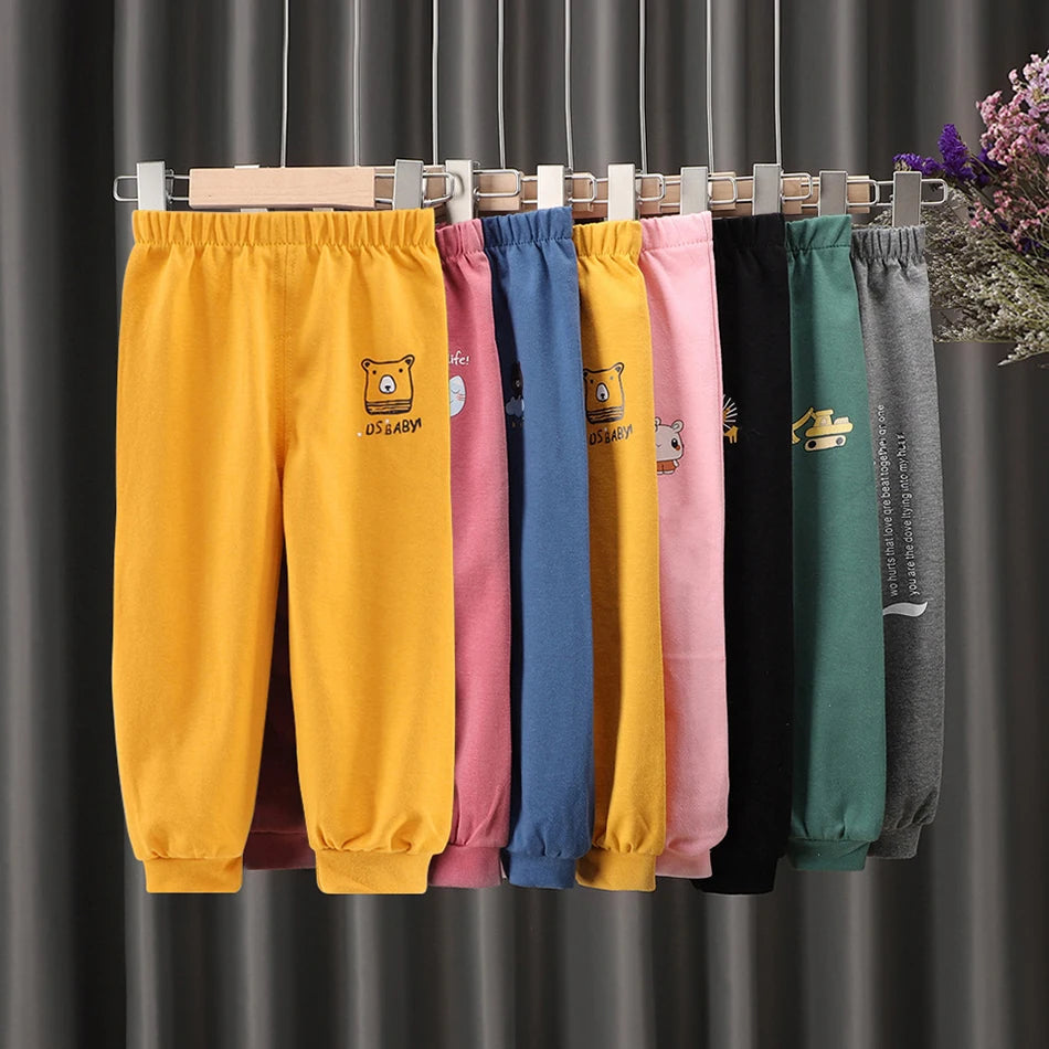 Colorful sweatpants hanging on a rack against a dark curtain background