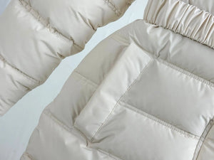 Close-up of a beige puffer jacket with quilted pattern on a light gray background