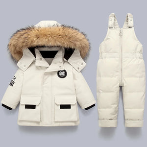 White winter coat with fur hood and matching snow pants on a light gray background