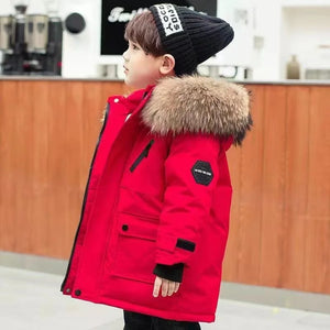 Child wearing a red winter coat with fur hood in an indoor setting