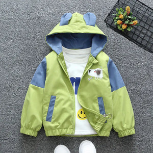Children's green and blue jacket with cartoon design on a gray surface