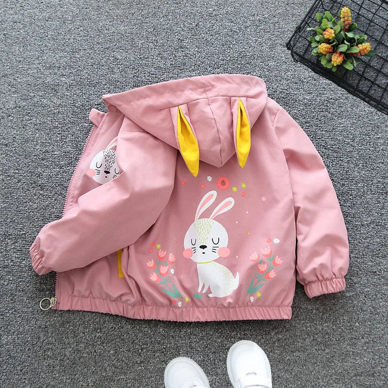 Pink children's jacket with bunny design on a gray floor.
