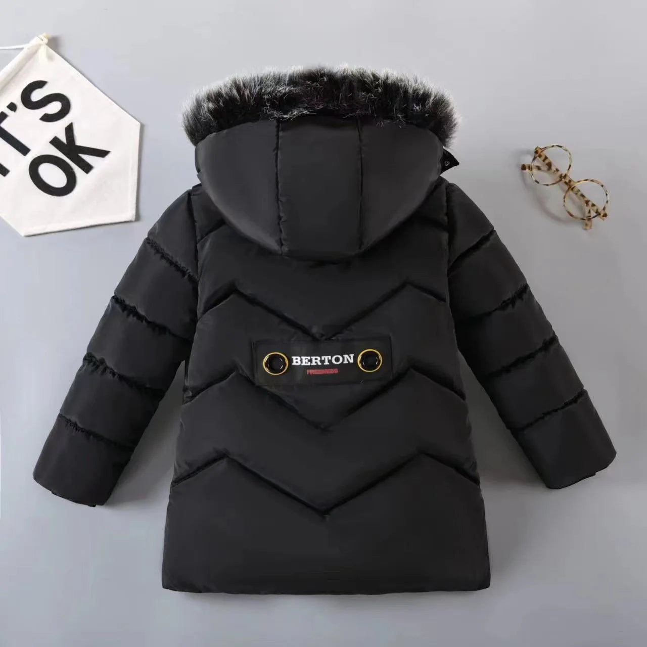 Black puffer jacket with fur hood on a gray background