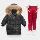 Black camouflage puffer coat with fur hood and red puffer pants on a white background
