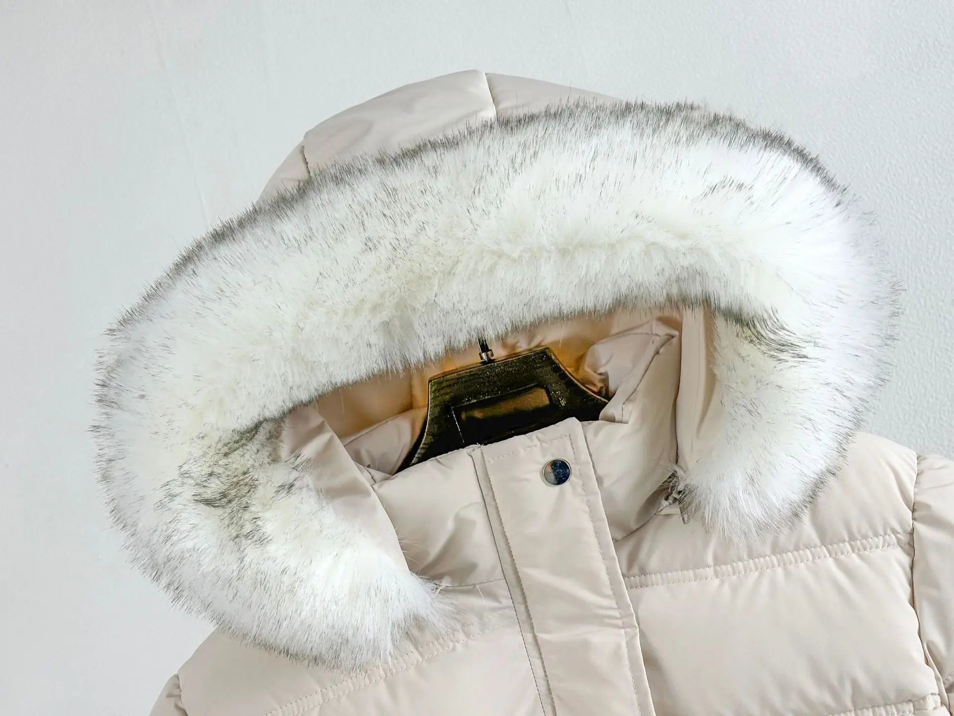 White puffer jacket with a large fur hood on a light gray background