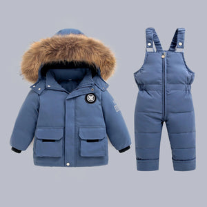 Blue children's winter coat with fur hood and matching snowsuit on a gray background