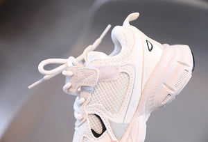 White sneaker with black logo on a gray background