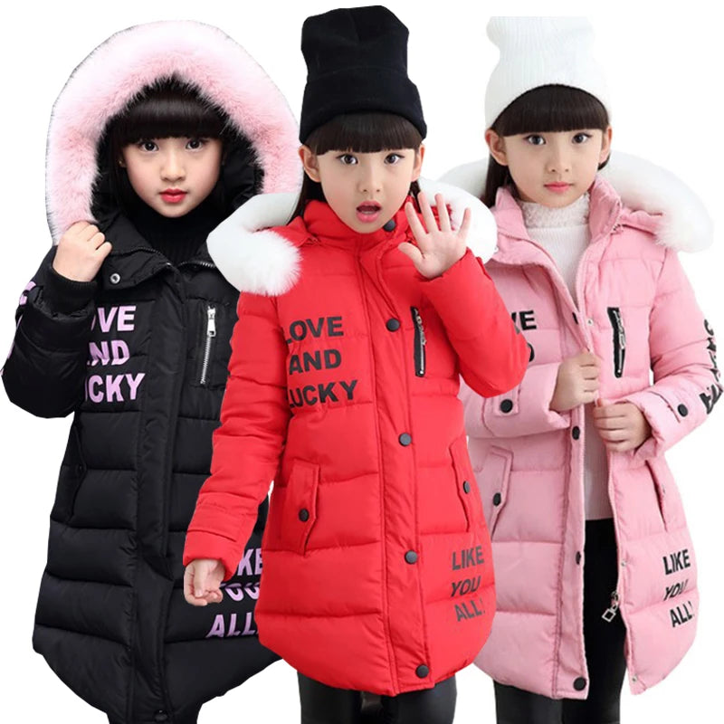 Three children wearing winter jackets with fur-lined hoods on a white background.
