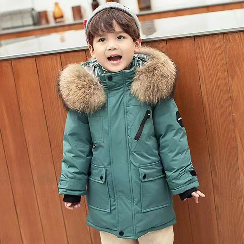 Child wearing a teal coat with a fur-lined hood in a kitchen setting