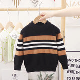 Children's striped sweater on a hanger against a white wall with text
