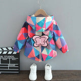 Colorful geometric-patterned jacket with a butterfly design on a hanger, paired with white sneakers.