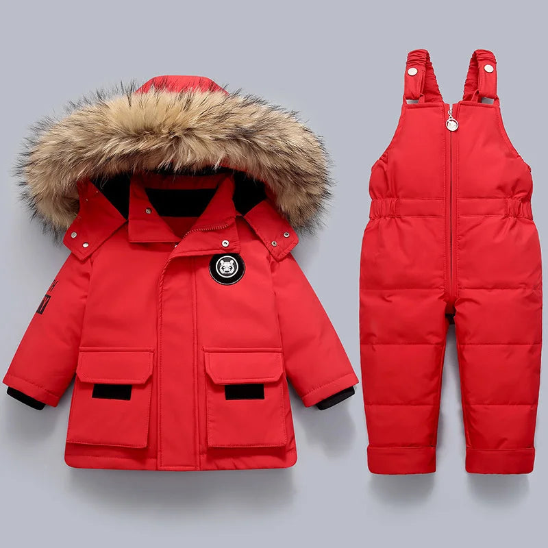 Red winter jacket with fur hood and red snowsuit on a gray background